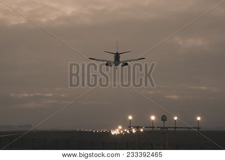 A Passenger Plane Is Landing On The Background Of The Twilight, Photo In Retro Style