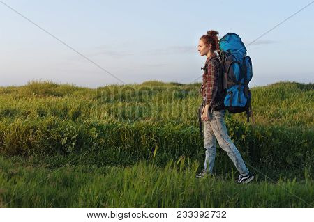Hiker Girl Is Traveling With A Backpack On The Landscape Background