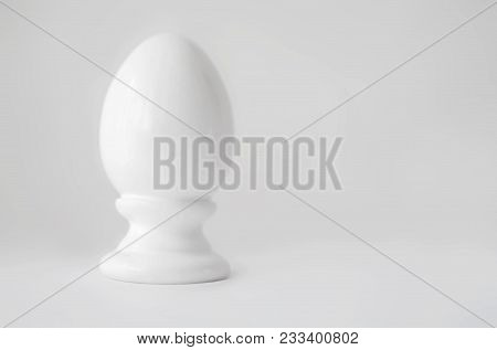 Single White Decorative Ceramic Statuette Egg In Eggcup On Gray White Blurred Background With Copy-s