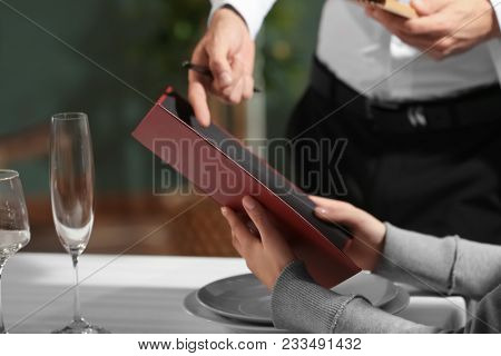 Waiter showing menu to client in restaurant