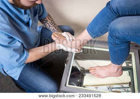 The Hands Of A Young Man Doctor Orthopedist Conducts Diagnostics, Foot Foot Test Of A Woman, For The