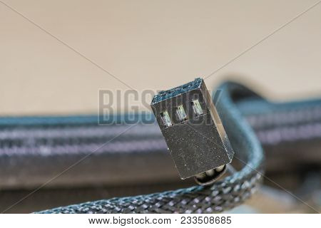 Closeup Of Black Three Pin Electrical Computer Connector With Braided Wire Covering Blurred Out In B