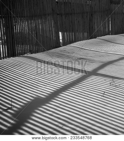 Shadow Of A Wooden Fence On White Snow On A Sunny Day