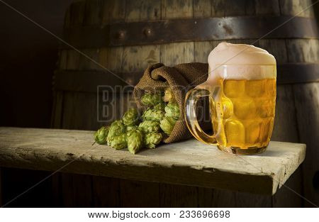Glass With Freshly Poured Beer Near Plates With Pistachios, Small Pretzels And Peanuts On Dark Woode