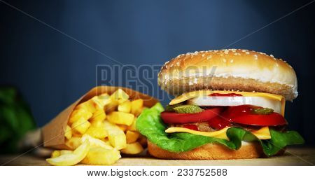 Close Up Of A Fresh Cheesburger And French Fries On A Wooden Table