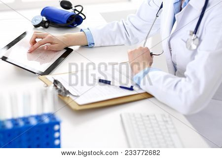 Woman Doctor Using Tablet Computer While Sitting At The Desk In Hospital Closeup. Cardiologist Check