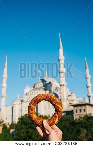 A Woman Is Holding A Traditional Turkish Bagel Named Simit In The Background Of The Blue Mosque In I