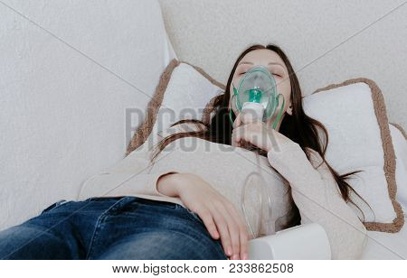 Use Nebulizer And Inhaler For The Treatment. Young Woman Inhaling Through Inhaler Mask Lying On The 