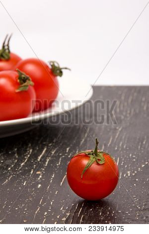 Red Tomato On A Black Board And Tomatoes On A Plate