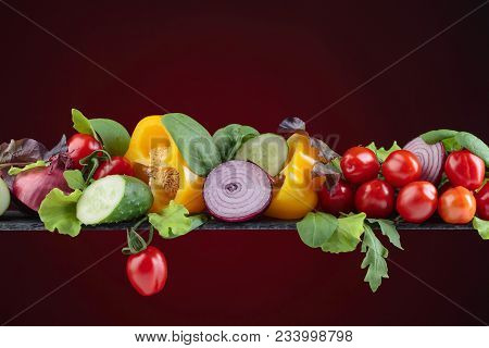 Various Fresh Summer Wegetables On Dark Red Background.