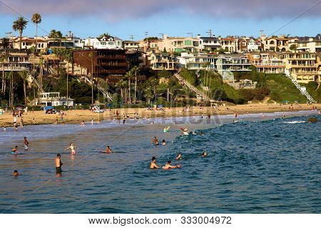 August 25, 2019 In Corona Del Mar, Ca:  People Swimming And Sunbathing At The Beach With Mansions On