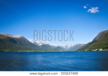 Isfjorden Is The Beautiful Blue Fjord At Andalsnes, Norway, With Homes At The Base Of The Mountains 