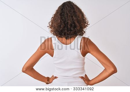 Young brazilian woman wearing casual t-shirt standing over isolated white background standing backwards looking away with arms on body