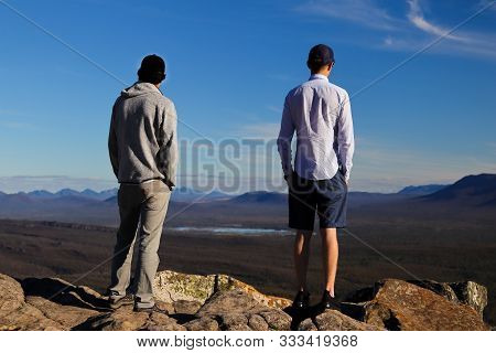 Two Young Men Contemplating The Horizon From A Cliff