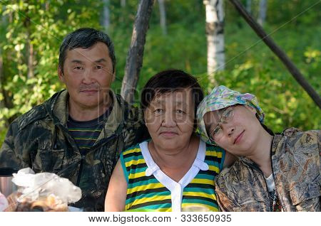 Family Portrait Of Two Elderly And One Young Daughter Yakut Asians In The Northern Forest At The Tab