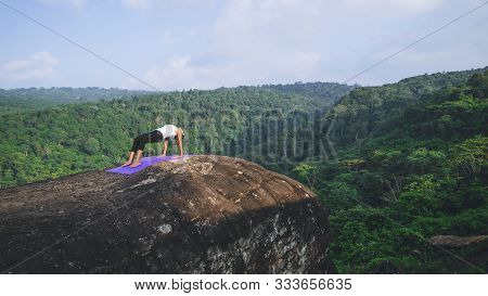 Asian Women Relax In The Holiday. Play If Yoga. On The Moutain Rock Cliff. Nature Of Mountain Forest