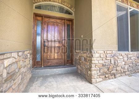Brown Wooden Front Door Of Home With Sidelights And Arched Transom Window