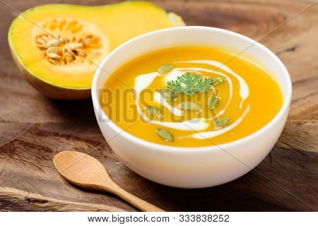 Butternut Squash Soup With Pumpkin Seeds In Bowl And Fresh Butternut Squash On Wooden Background