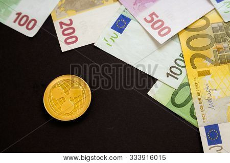 Ripple Coin Next To Euro Bank Notes On Black Background. Digital Currency, Block Chain Market. Euro
