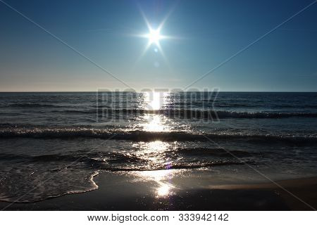 The Sun Sets Over The Sea At Sunset, On The Horizon, It Looks Like A Fake Star. The Sea Is Calm In F