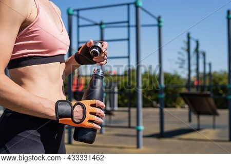 Close Up Of Woman Hands In Sport Gloves Holding Water Bottle On Sports Ground