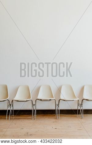 Five empty white chairs in a room