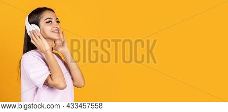 Side View Portrait Of Young Beautiful Woman In Headhones Isolated Over Yellow Background