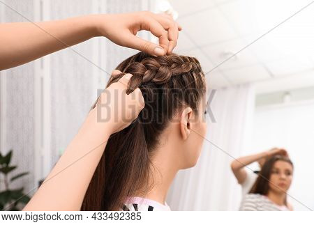 Professional Stylist Braiding Client's Hair In Salon