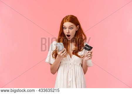 Shocked And Startled Young Caucasian Redhead Girl Seeing Something Shook On Her Bank Account Via Sma
