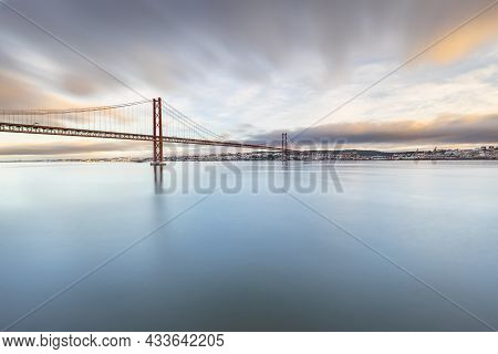 The 25 De Abril Suspension Bridge Over Tagus River In Lisbon, Portugal At Sunrise