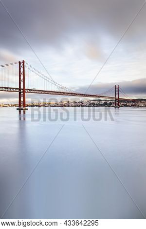 The 25 De Abril Suspension Bridge Over Tagus River In Lisbon, Portugal At Sunrise