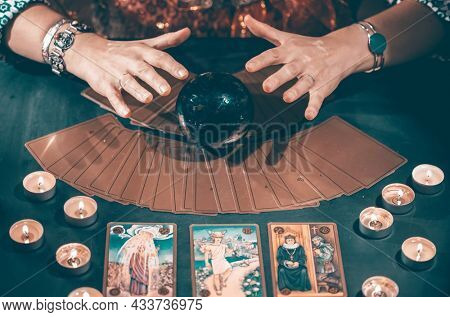Fortune teller with tarot cards on table near burning candles.Tarot cards spread on table with crystal ball.Forecasting concept.