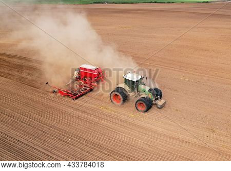 Agricultural Tractor On Cultivating Field For Sowing Seeds. Farming And Seeding Concept. Seed Sowing