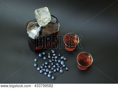 Homemade Blueberry Liqueur, A Sweet Alcoholic Drink In Two Glasses And A Bottle On A Black Backgroun
