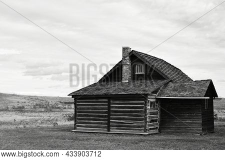 A Black And White Image Of An Old Abandoned Log House On The Alberta Prairies.