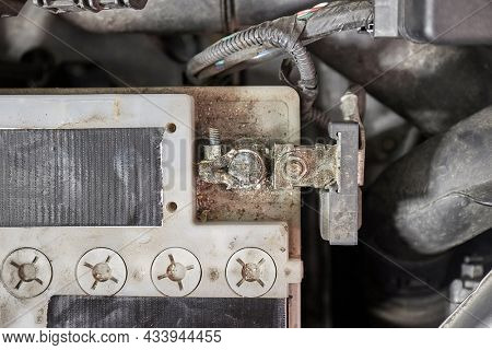 Old car starter battery inside the engine bay viewed from above top down, negative terminal connection closeup