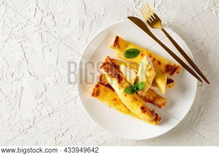 Blintz, Rolled Filled With Sweetened Cottage Cheese Pancakes Or Crepes On A White Plate On A Wooden 