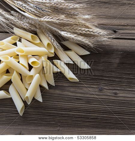 Spilled raw pennoni pasta on wooden table