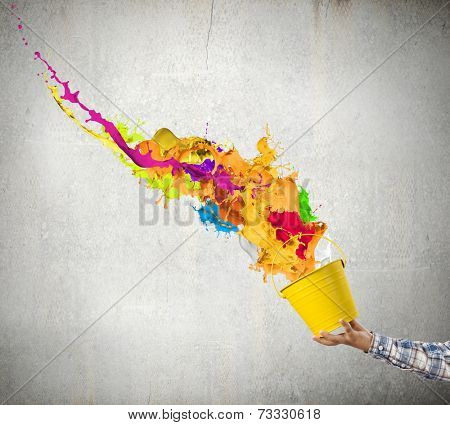 Close up of hand splashing colorful paint from bucket
