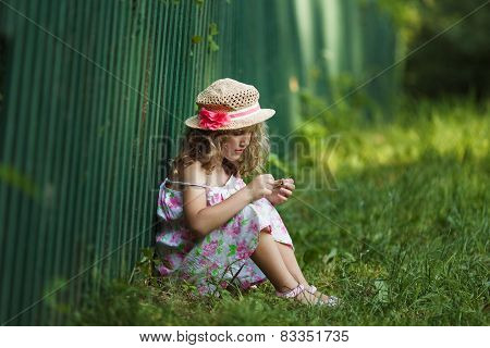 Girl Sits Leaning Against A Fence
