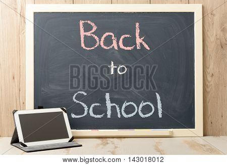 back to school written on blackboard with digital tablet
