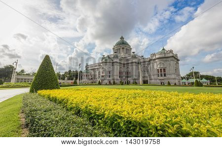Bangkok Thailand - July 1 2016: Ananta Samakhom Throne Hall with green lawn and yellow bush in front of which having cloudy blue sky as background