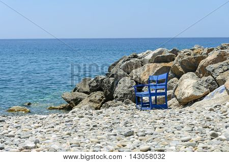Lonely bench at stone beach of Paleochora town on Crete island, Grecee