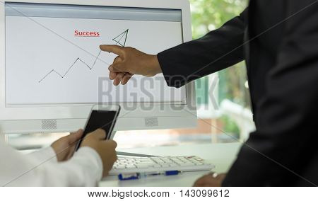 Business people look at graphs and charts being demonstrated on the screen of computer