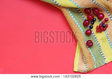 Summer background with berries on a yellow material. Top view composition.