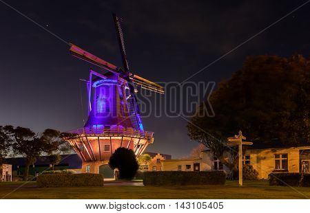 De Molen windmill of Foxton New Zealand with it's night color lights on.