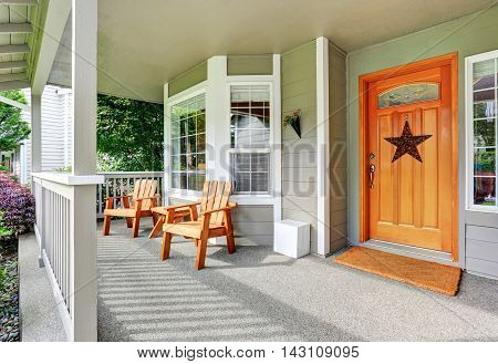 Spacious Concrete Porch With Wooden Chairs And Nice Entry Door.