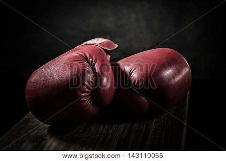 Old boxing gloves lay on the wooden floor. The concept of retirement