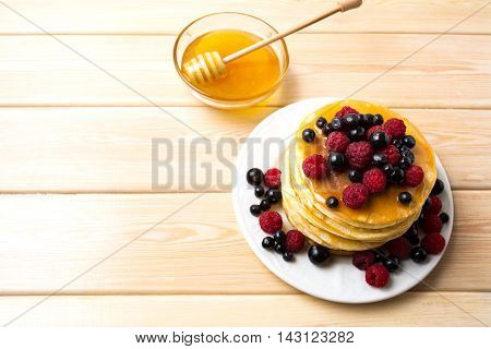 Breakfast pancakes with honey and fresh berries. Stack of homemade pancakes served with blueberry raspberry and blackcurrant.