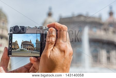 Male hands taking a photo of Piazza Raffaele de Ferrari square of Genova with Palazzo della Nuova Borsa Valori in background. Liguria Italy.